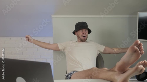 Man relaxing, in indoor modern room with a laptop and mirror, with laptop, mirror, from a neutral front-facing view perspective, with white, black accents, and relaxed mood.