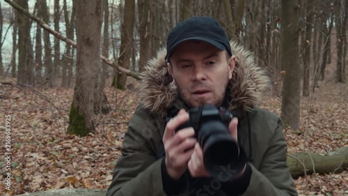 photographer taking focused photos in the woods with leaves and a wooden floor, brown and green tones, nature photography, outdoor adventure, focused and engaged, close-up perspective, eye.