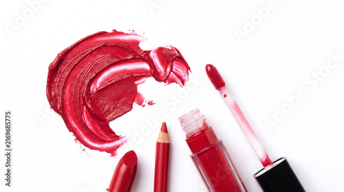 Textured Red Lipstick Smear with Makeup Products on White Surface