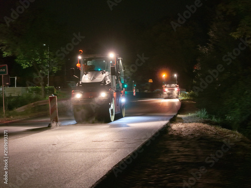 Nighttime road construction and asphalt resurfacing with heavy machinery