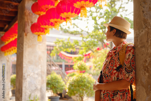 Young female tourist walks through historic Lhong 1919 courtyard in Bangkok Chinatown. Woman enjoys heritage Chinese architecture, ancient brick buildings, and cultural atmosphere.