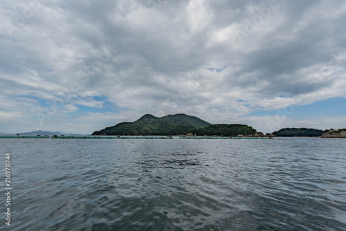 Fotografía Cloudy Seto Inland Sea with green island and oyster farming rafts