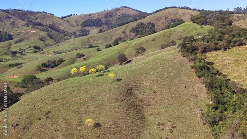 Aerial view of hills in Brazilian countryside under a blue sky.