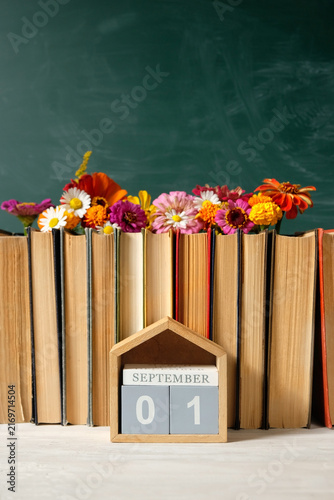 September calendar. calendar block with date 1 September, books and flowers on table against chalkboard. Back to school, Education, beginning of the school year, Knowledge Day