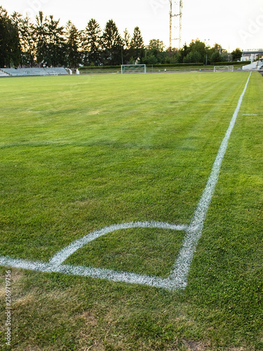 Detailed view of soccer field corner markings on green grass, capturing the surface texture and outdoor sports atmosphere.