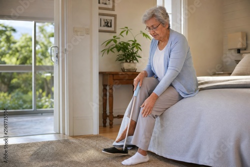 Senior woman using long-handled shoehorn for independent dressing