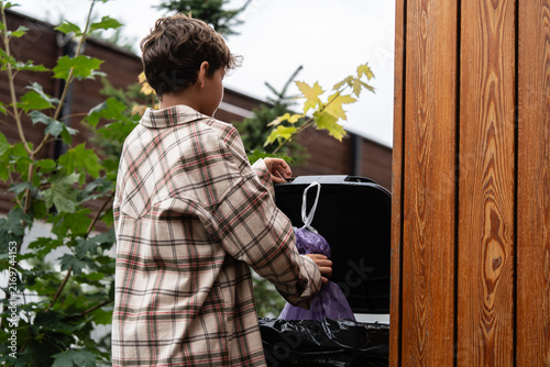 Принти на полотні Man throws a purple garbage bag into a street trash bin, promoting cleanliness and responsibility