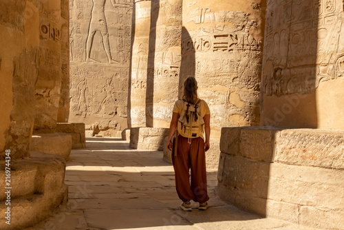 Canvastavla Person explores ancient columns with hieroglyphs inside an archaeological site in Egypt during daylight