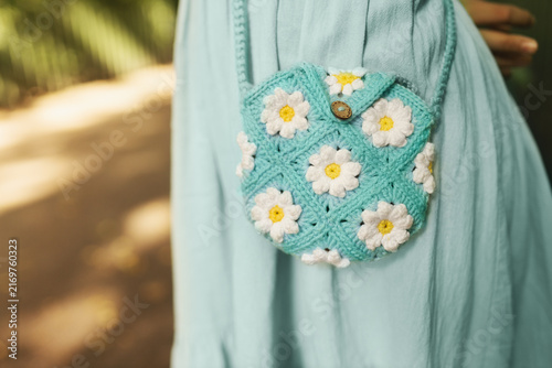 Woman in mint dress holding handmade turquoise crochet daisy purse