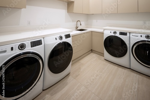 Foto Modern  laundry room featuring double washing machines and dryers with cabinets