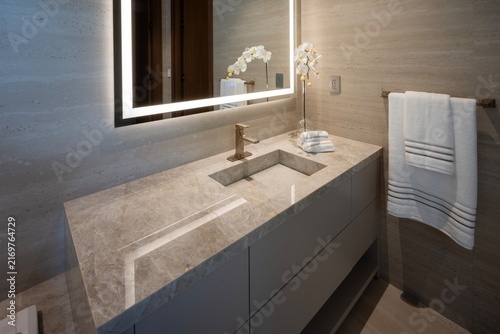 Modern luxury bathroom vanity with integrated marble sink, brass faucet, and backlit LED mirror.