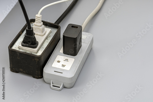 фотографія Close-up image of two worn and dusty electrical power strips overloaded with mul