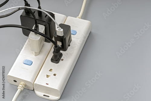 Obraz na płótnie Close-up of a white electrical power strip overloaded with several black plug ad