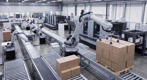 An automated industrial robotic arm lifts and stacks packaged cardboard shipping boxes neatly onto a wooden transport pallet next to a conveyor line