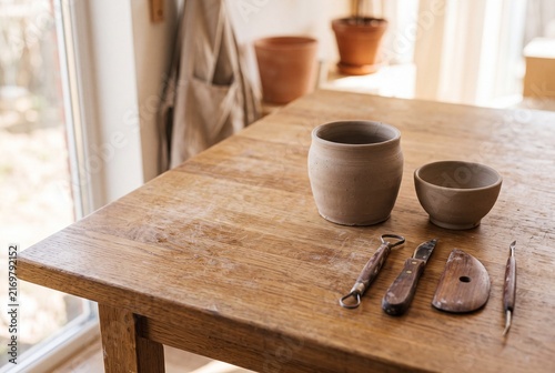Ceramic tools and unfinished clay vessels on an artisan table