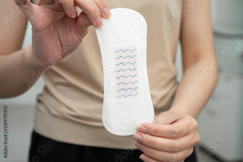Quadro su tela Asian woman holding sanitary napkin pad for hygiene menstrual period cycle protection