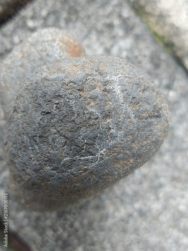 A close up view of a textured grey stone on a paved surface.