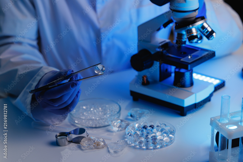 Fototapeta premium Gemstone laboratory closeup with diamonds and microscope for jewelry inspection background and scientific testing, blue light