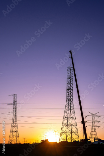 Crane Erecting Steel Transmission Tower Near Power Lines
