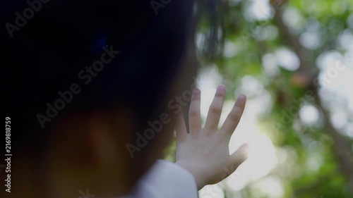 The young woman is pulling her hand toward the sunlight.