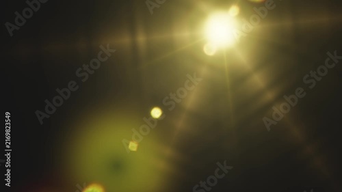 Bright golden lens flare effect glowing against a dark background in video sequence