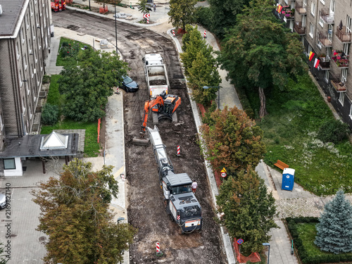 Daytime road construction and asphalt resurfacing with excavator in urban area