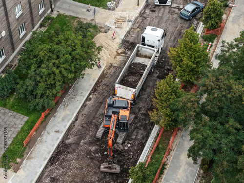 Daytime road construction and asphalt resurfacing with excavator in urban area
