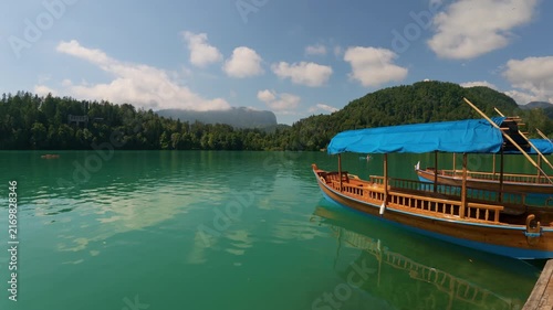 Calm turquoise water of Lake Bled with traditional wooden Pletna boats moored near the shore