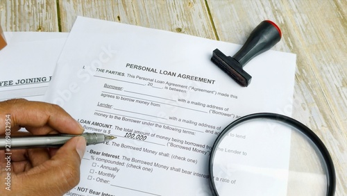 Hand signing personal loan agreement with stamp.