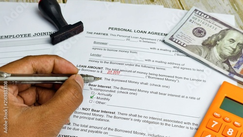 Hand filling personal loan agreement form with cash.
