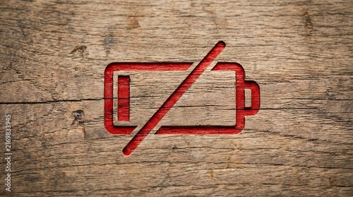 Red empty battery symbol placed on a natural wood surface representing low energy and power depletion background battery empty low level charge power energy symbol icon warning status red wood wooden