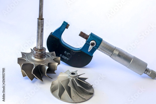 Canvas Print Standing turbocharger turbine shaft compressor wheel impeller and outside micrometer on white background