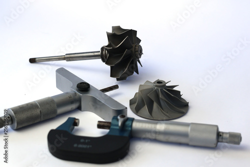 Foto Set of turbocharger turbine shaft compressor wheel and precision micrometers on white background