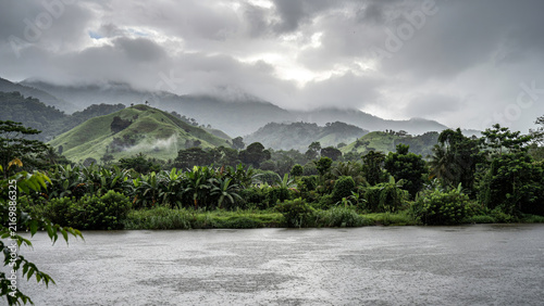 Misty riverside landscape with dense green hills and rocky riverbank under