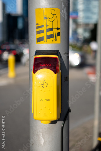 Yellow pedestrian crossing touch button in the city of Warsaw. Selective focus. vertical photo.