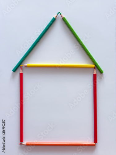 Colorful pencils arranged in the shape of a simple house on a white background, symbolizing home, family, housing, education and creativity.