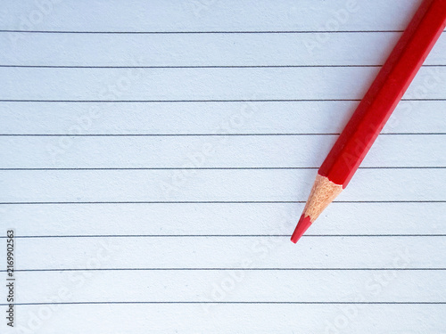 Red colored pencil on lined white paper with copy space
