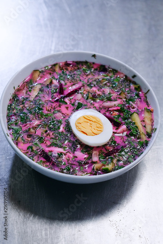 Canvas Print Vibrant pink cold beet soup topped with a halved hard-boiled egg, fresh dill and cucumber slices served in a white bowl on metal surface