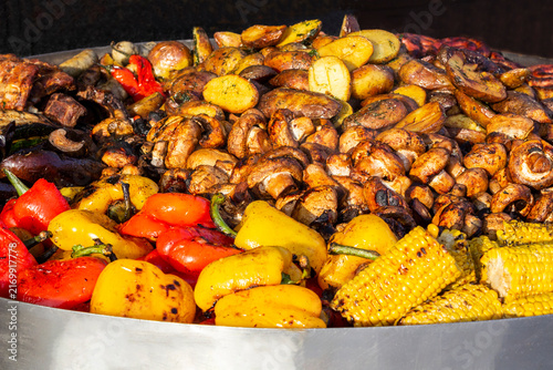 Street food: fried corn, peppers, and mushrooms in a large frying pan