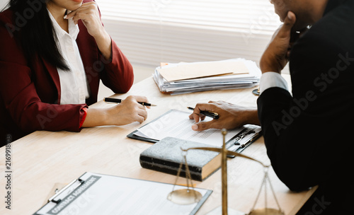 Фотография Legal Consultation: Two professionals sit at a desk, carefully reviewing and signing legal documents