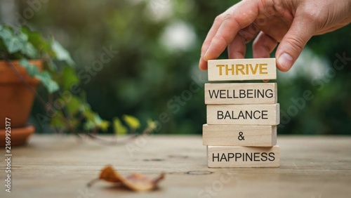 Businessman hand placing wooden block with thrive text for life balance and happiness concept.