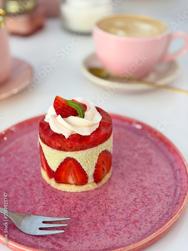 High angle shot of strawberry mini mousse cake on pink ceramic plate with coffee cup background. High quality photo