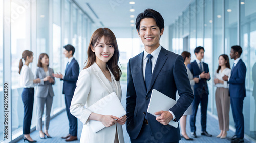 Tapety artystyczne 活気あるオフィスビル内でノートパソコンを手にする20代〜30代の男女社員（リクルート・チーム・働き方改革）