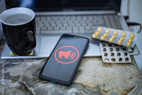 Sick day at office desk with smartphone alert and medicine.