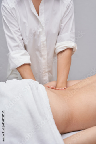 Foto Female Massage Therapist Pressing Lower Back Of Client During Body Treatment In Soft Neutral Spa Room