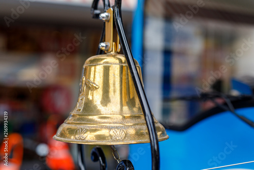 Fotografie Close-up of a weathered golden bell with seashell carvings, reflecting light in