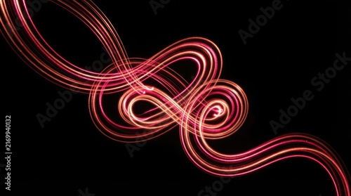 Abstract long exposure light trails forming elegant glowing loops and intricate curves against a pitch black background for modern digital design