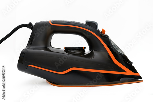 Canvastavla Black iron with orange inserts for ironing clothes at home.