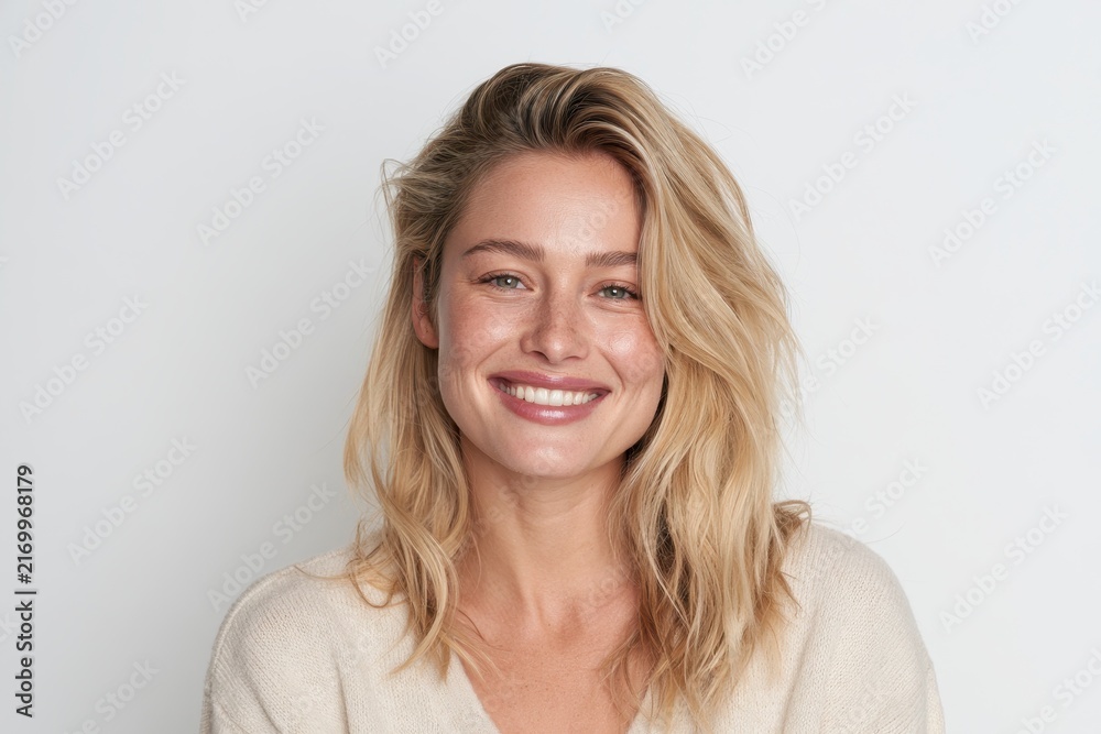 Fototapeta premium Studio portrait of a joyful woman with fair hair in casual wear against a plain backdrop