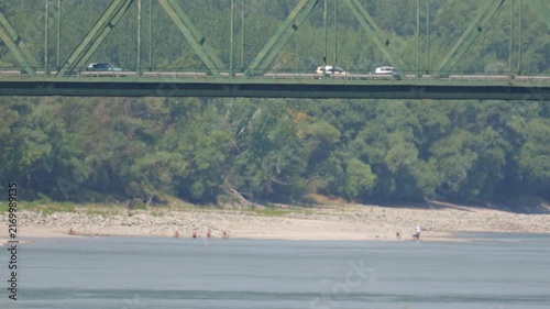 Traffic crossing Medve bridge above people using newly exposed Danube riverbank during extremely low water levels in summer